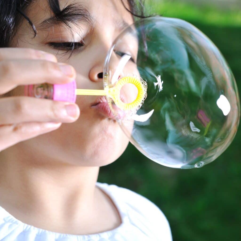 Une jeune fille qui souffle de façon continu dans une bulle de savon