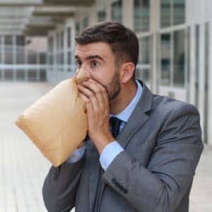 Un homme qui respire dans un sac à papier pour mieux maitriser son angoisse